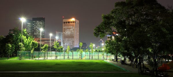 Outdoor sport stadium at State Railway Public Park also called Suan Rot Fai against modern buildings at night in Bangkok Thailand